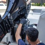 Mechanic is installing speed boat engine , a new engine on an aluminum boat.