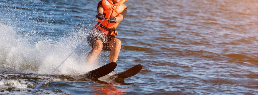 Woman riding water skis closeup. Body parts without a face. Athlete water skiing and having fun. Living a healthy lifestyle and staying active. Water sports theme. Summer by the sea. Banner for website.
