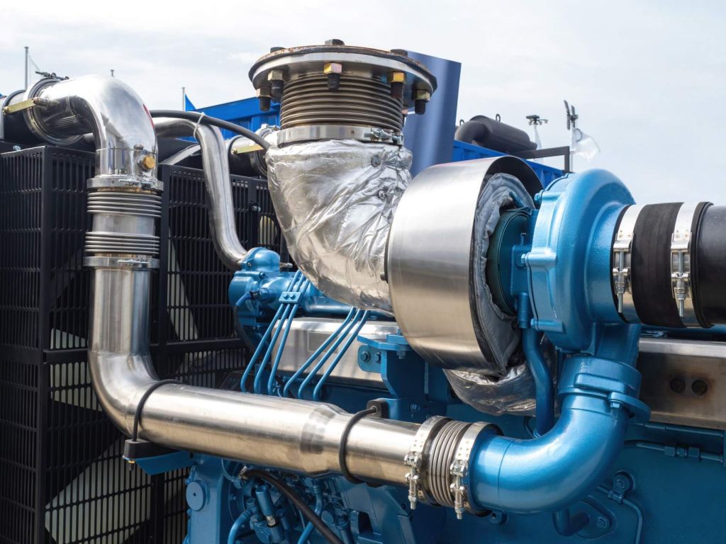 Boat motor fragment. Engine with turbocharger. Ship blue engine close-up. Fragment of ships engine with propeller. Concept of maintenance and repair of ship motors. Huge open air boat motor
