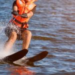 Woman riding water skis closeup. Body parts without a face. Athlete water skiing and having fun. Living a healthy lifestyle and staying active. Water sports theme. Summer by the sea. Banner for website.
