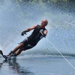 A water skier in his 60's preforming water skiing sport on a lake.
